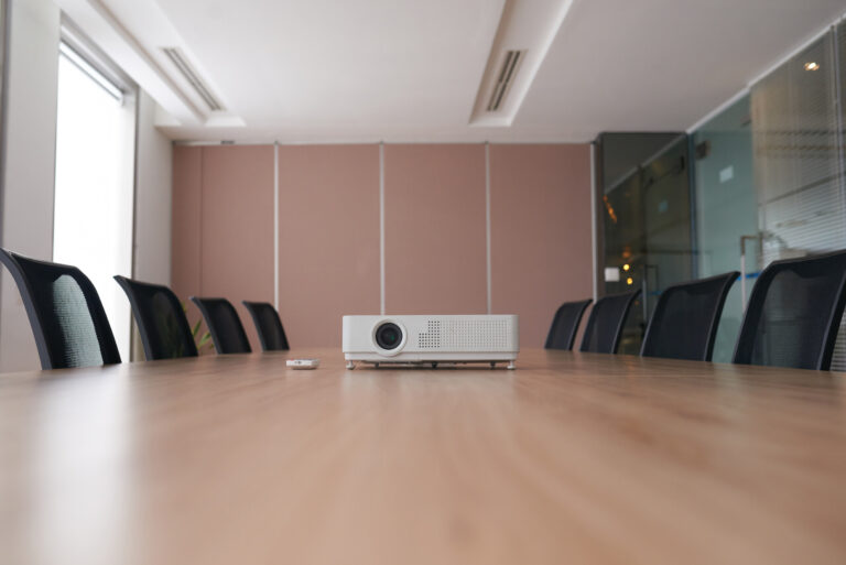 a projector and remote on a boardroom table, waiting for someone to learn how to install a projector